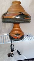 Full view of the vintage wooden lamp showing tiered shape, painted Brazilian scenery, and electrical cord.