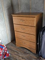 Front view of wooden dresser with four drawers and metal handles, wood medium brown finish, clean and in good condition.