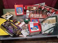 Wide view of assembled Christmas decorations including boxed ceramic houses, wooden candle holders, assorted ornaments, trays, holiday signs, and other decorative items on a table.