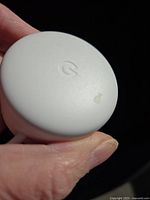 Top view of white Google Nest Mini showing 'G' logo with a slight smudge.