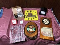 Multiple clocks arranged on a pink surface, showing variety of styles and materials, along with a small box of clock parts and a price tag of $2.50