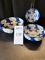 Three blue and white leaf patterned nesting bowls shown with auction lot tag; backs and sides visible