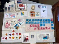 Photo showing mixed collection of postage stamps including flower, flag, bird, and numeric value stamps with some organized in clear plastic holders or on cards.