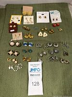 Top-down photo showing all costume earrings laid out on green fabric to depict full selection.
