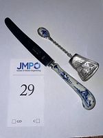 Two-piece lot showing a serrated knife with a ceramic Delft-style handle and an ornate metal scoop with embossed design.
