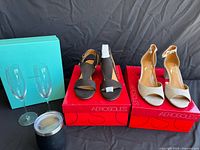 Photo of two pairs of Aerosoles open toe pumps on red boxes, Tiffany flute box, two champagne flutes, black insulated cup
