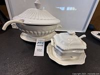 Ivory white Copeland Spode Gadroon sauce tureen set on black surface displaying tureen with lid and ladle, alongside small lidded sauce dish and plate.
