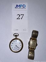 Front view of Bulova wristwatch and Elgin pocketwatch with lot tag