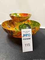 Side view of colorful large chip bowl and smaller attached elevated dip bowl showing painted fruits and vegetables motif