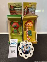 Front view of mouse and elf stocking hangers in original boxes with Mickey and Minnie ornament in front