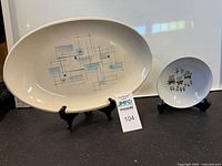 Full shot of both items on display stands, showing the 15-inch oval Oasis Franciscan platter and the 6-inch round children's bowl with bear designs.