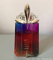 Front view of Alien Thierry Mugler perfume bottle showing multicolor lacquered finish and gold spray top, bottle approximately 75% full.