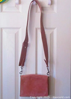 Full view of nail-studded detachable crossbody strap and front of bag in nude/blush pink suede.
