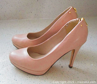 Side view of the nude pink/beige high heel shoes showing the gold stud and zipper hardware on the back and overall shape and color of the shoes.