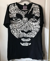 Front view of black Desigual t-shirt with large 3D white text face print.