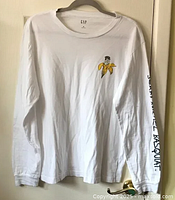 Full front view of white long sleeve t-shirt with banana graphic on right front chest and black signature text on right sleeve