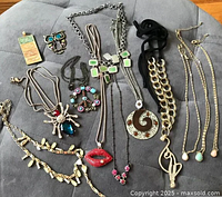 Photo showing 11 necklaces and 2 pendants with various styles and stones on a grey background