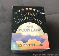 Front view of Lunar Abundance Mini Moon Lamp box showing colorful packaging with text and moon phases.