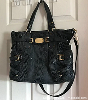 Front view of Michael Kors Gansevoort handbag in dark blue patent leather snakeskin pattern showing the gold hardware, top handles, and logo plaque.