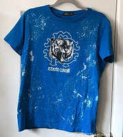 Front full view of blue t-shirt with white spot ink detail and tiger face graphic.