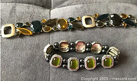 Top view of both bracelets laid out on a gray fabric background, showing color and stone arrangement of each bracelet.