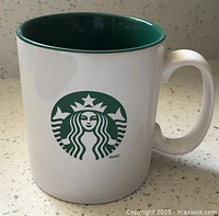 Front view of white Starbucks mug displaying classic green siren logo and green interior.