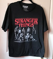 Full view of black Stranger Things t-shirt hanging, showing front graphic.