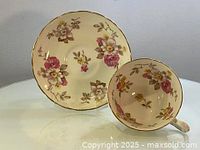 Teacup and saucer displayed side by side showing floral pattern and gold trim on both items