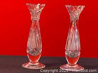 Pair of vintage crystal cut glass bud vases shown against a red background, highlighting their faceted edges and detailed cut glass patterns.