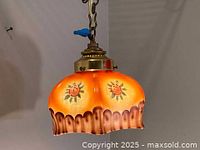 Side view of vintage glass pendant showing hand painted sunflower motifs and scalloped brown edge