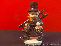 Front view of the Hummel chimney sweep figurine showing the dark outfit, top hat, orange neckerchief, ladder on shoulder, and detailed face.