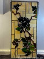 Full view of the stained glass grape leaves door panel hanging on the wall.