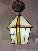 Front side view of vintage stained glass pendant lamp showing the windowpane style design with cream and amber yellow glass panels.