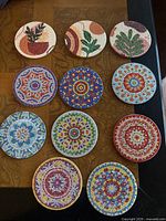 Top-down view of all 11 coasters on a wooden surface showing the detailed diamond mosaic and painted gem designs.