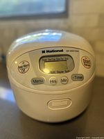 Front view of the National SR-MM10NS electric rice cooker with LCD display and control buttons visible.