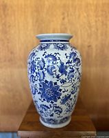 Front view of the vintage blue and white floral porcelain vase on wooden stand against wood background