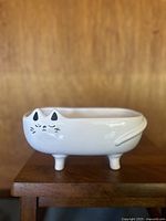 Front view of the vintage ceramic cat planter showing painted cat face, ears, legs, and tail detail, glossy finish.