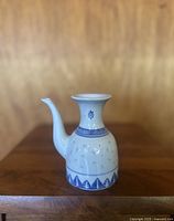 Front view of vintage Chinese soy sauce decanter showing curved spout, flared neck, and blue rice eye decorative band on white porcelain.