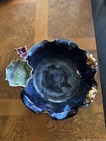 Top-down view of blue glazed porcelain bowl with lotus and frog decorations attached at rim.