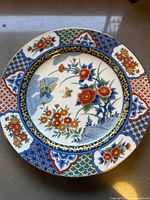 Front view of the vintage Imari-style salad plate showing intricate floral and butterfly design with segmented colorful rim decoration.