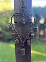 Front view of rusted iron heart wind chime with ten small iron bells hanging.