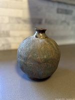 Front angled view showing the rounded body and narrow opening of the textured pottery vase