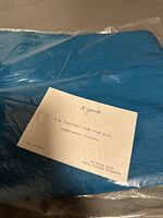 Blue Thai silk fabric folded and sealed in plastic with a label showing '3 yards' and factory information.