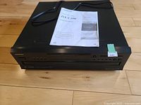 Front view of the Onkyo DX-C390 CD changer with manual on top, showing overall condition and appearance.