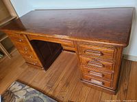Full view of vintage wooden desk from front-left angle showing drawers and desktop finish.