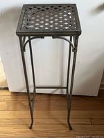Front view of the metal plant stand showing lattice square top and curved legs.