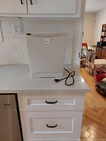 Front and side view of the white paper shredder with the power cord coiled on the counter.