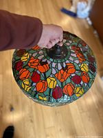 Top view of stained glass lampshade showing vibrant tulip flower design in red, orange, yellow colors.