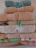 Stack of 8 towels in various colors and sizes tied with string, showing different textures and patterns.