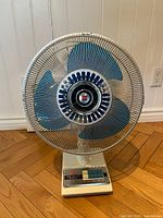 Front view of the vintage electric fan showing metal wire guard and blue blades.